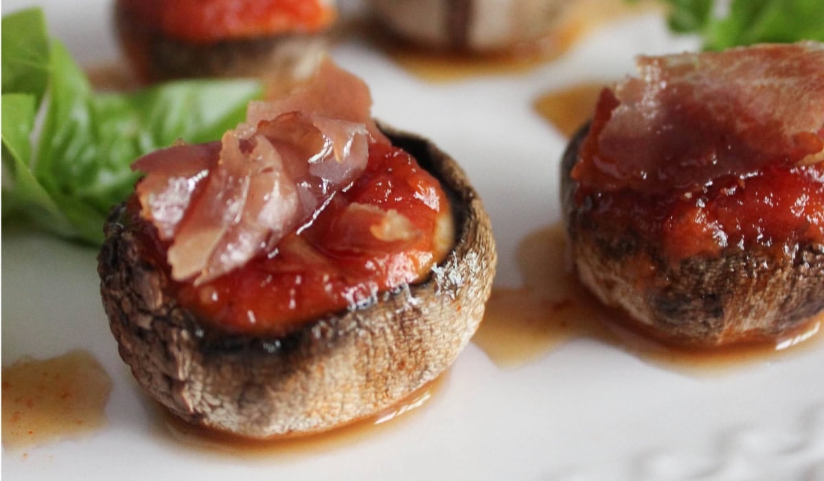 a close up of inside out stuffed pizza mushrooms on a white plate