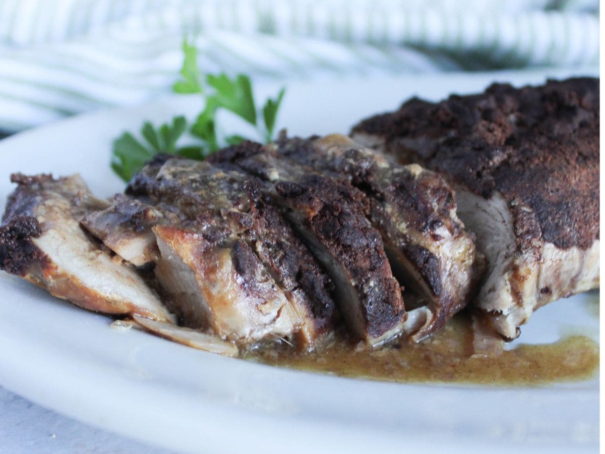 a close up view of slow cooker pork tenderloin sliced on a plate with gravy